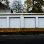 Row of four white single garages with up-and-over doors and autumn leaves in front – unpermitted outbuildings must be assessed separately in a market value appraisal