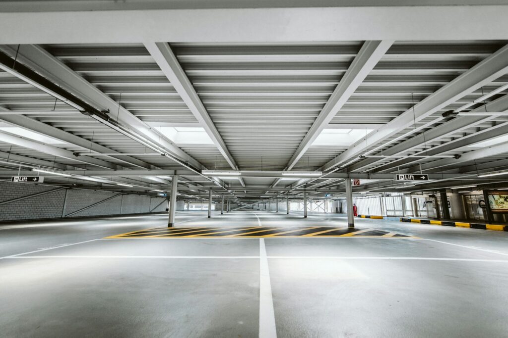 Leeres Parkdeck eines Parkhauses mit Fahrgassen, Stützen und Markierungen – bei Parkhäusern bestimmen Umschlag und Zustand der Fahrbahnplatten den Verkehrswert