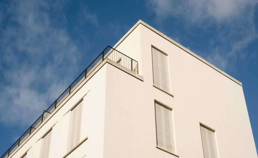 Modern apartment building with a roof terrace against a blue sky – a condominium and the common property of an owners' association