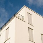Modern apartment building with a roof terrace against a blue sky – a condominium and the common property of an owners' association
